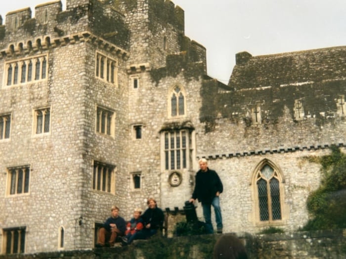 Gammelt bilde av 4 personer utenfor en gammel slottslignende bygning i Wales. 