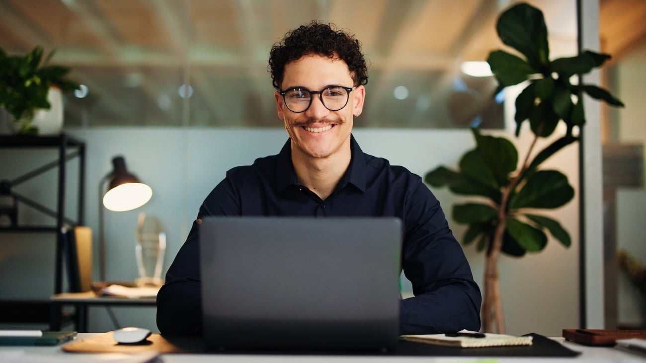 Formelt kledd forretningsmann som sitter konsentrert foran en PC på et kontor. 
