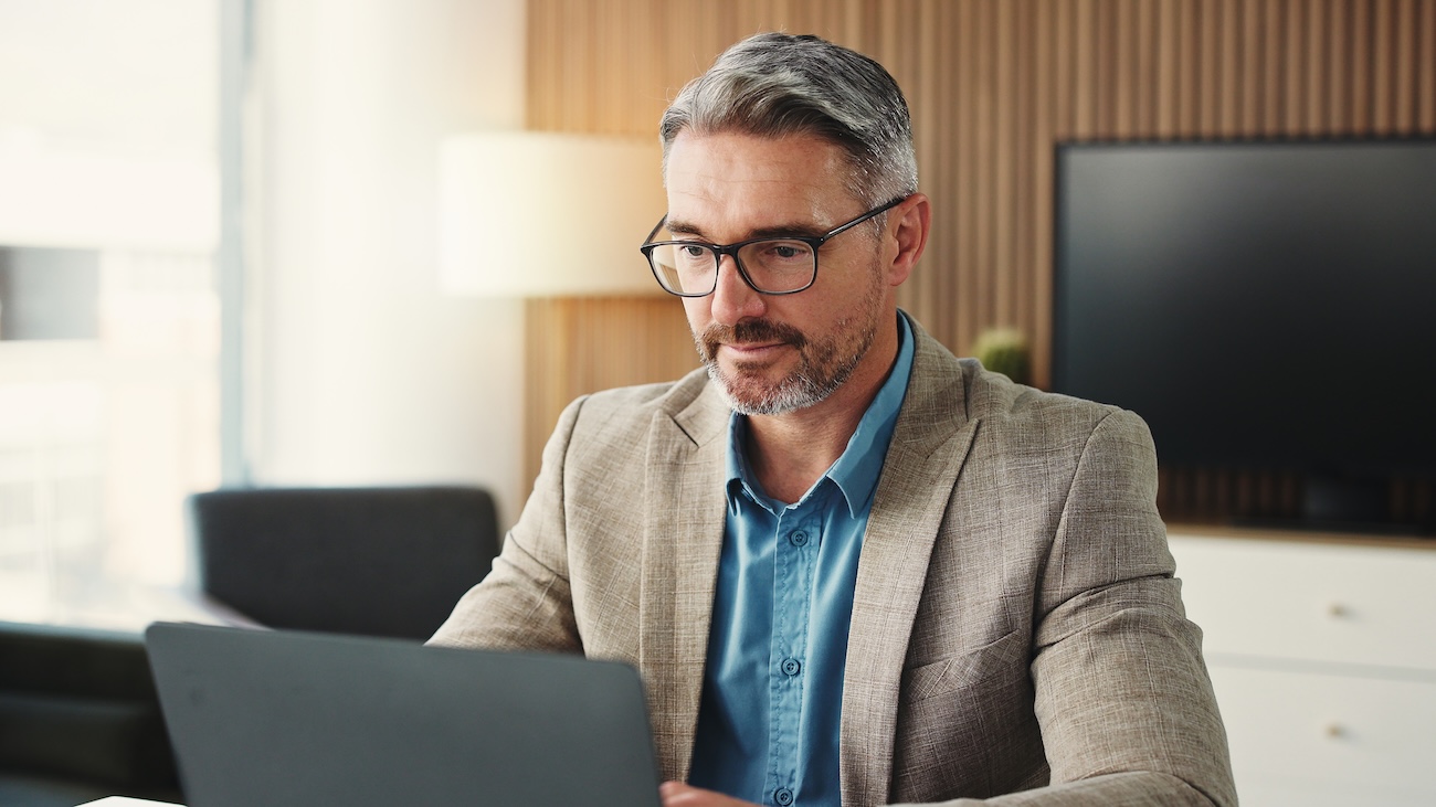 Formelt kledd forretningsmann som sitter konsentrert foran en PC på et kontor. 