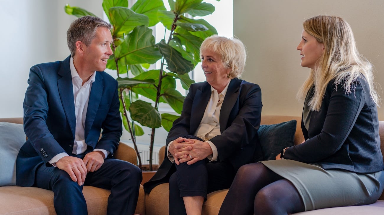 Tre av Econas advokater i samtale med grønn plante i bakgrunnen.