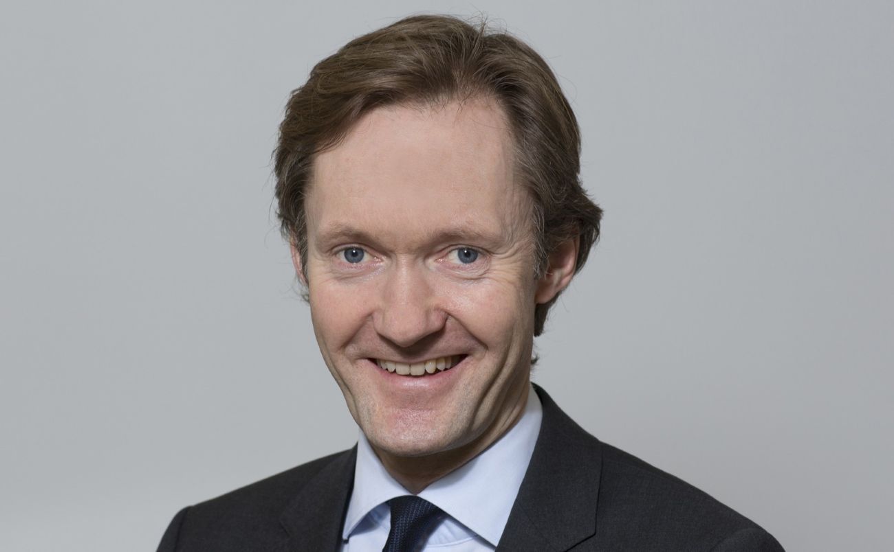 Formelt kledd mann som smiler bredt til kamera.