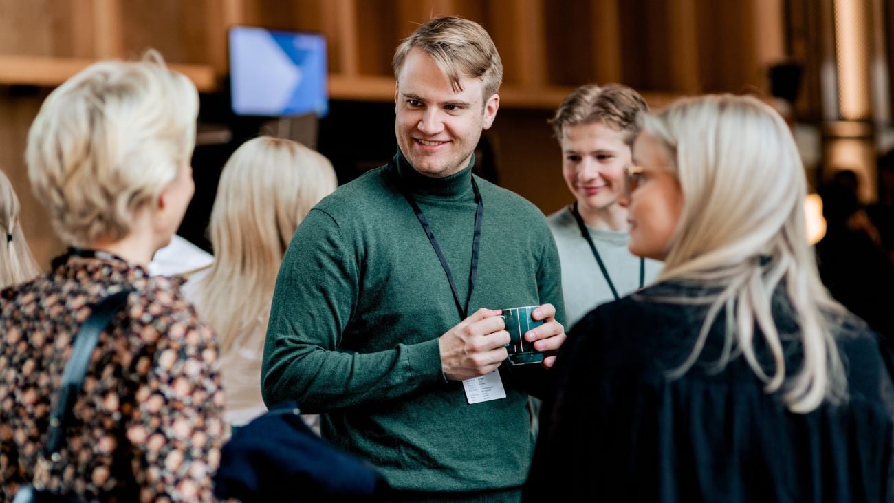 Stående gruppe mennesker som prater i konferansesetting
