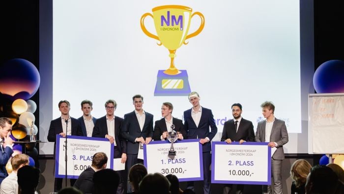 De tre lagene som fikk pallplass under NM i økonomi 2026 som står på scenen og mottar applaus.