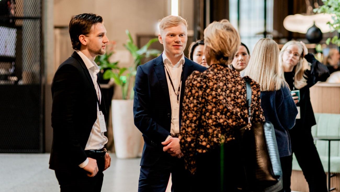 Stående grupper av folk som prater i en lobby i en arbeidskontekst