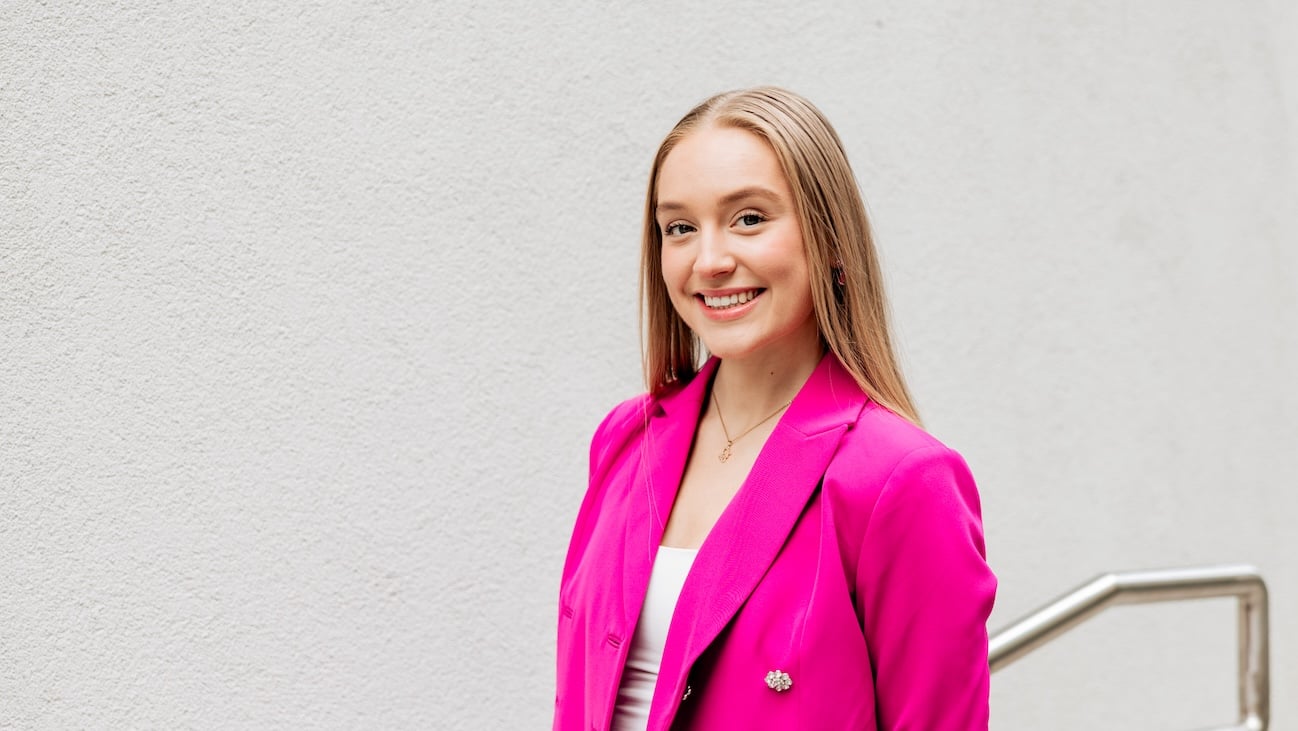 Ung kvinne i rosa dress med beige bakgrunn.