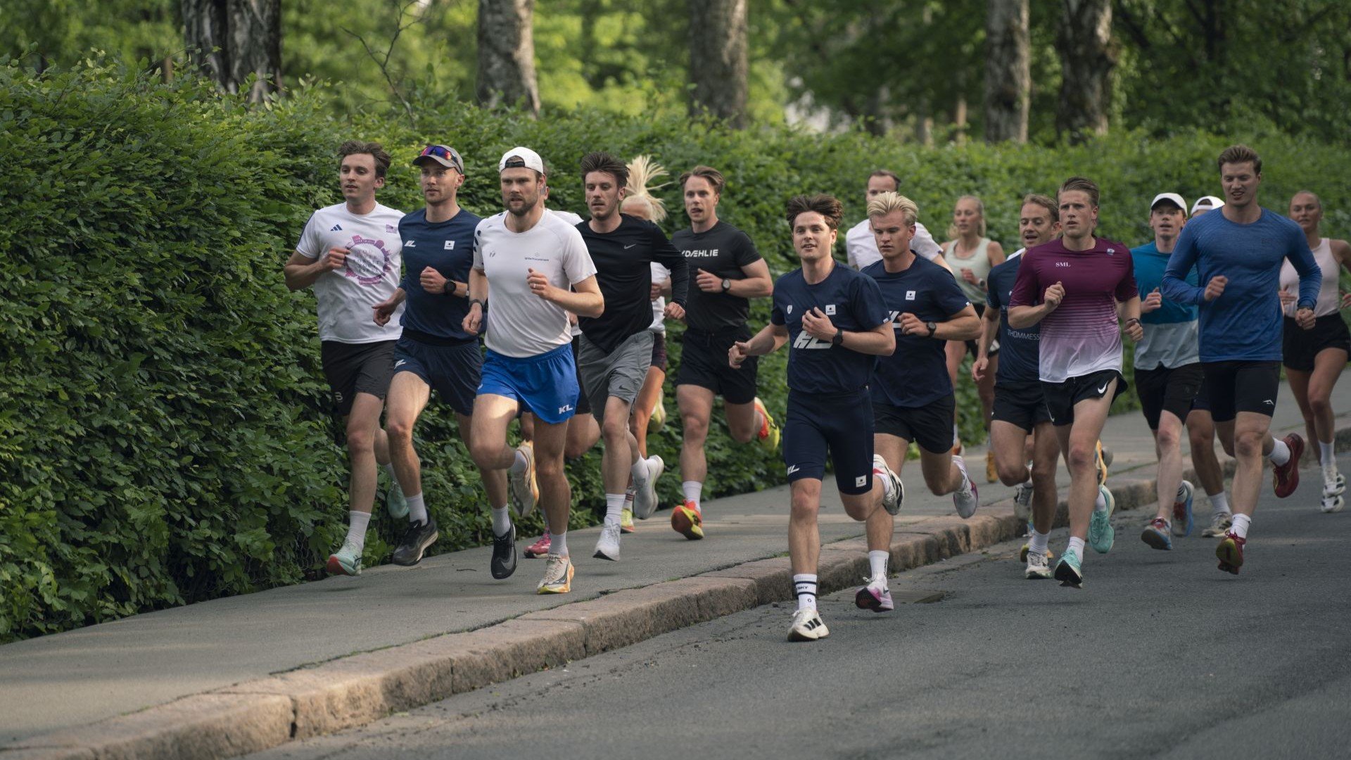 Stor gruppe voksne som jogger på fortau.