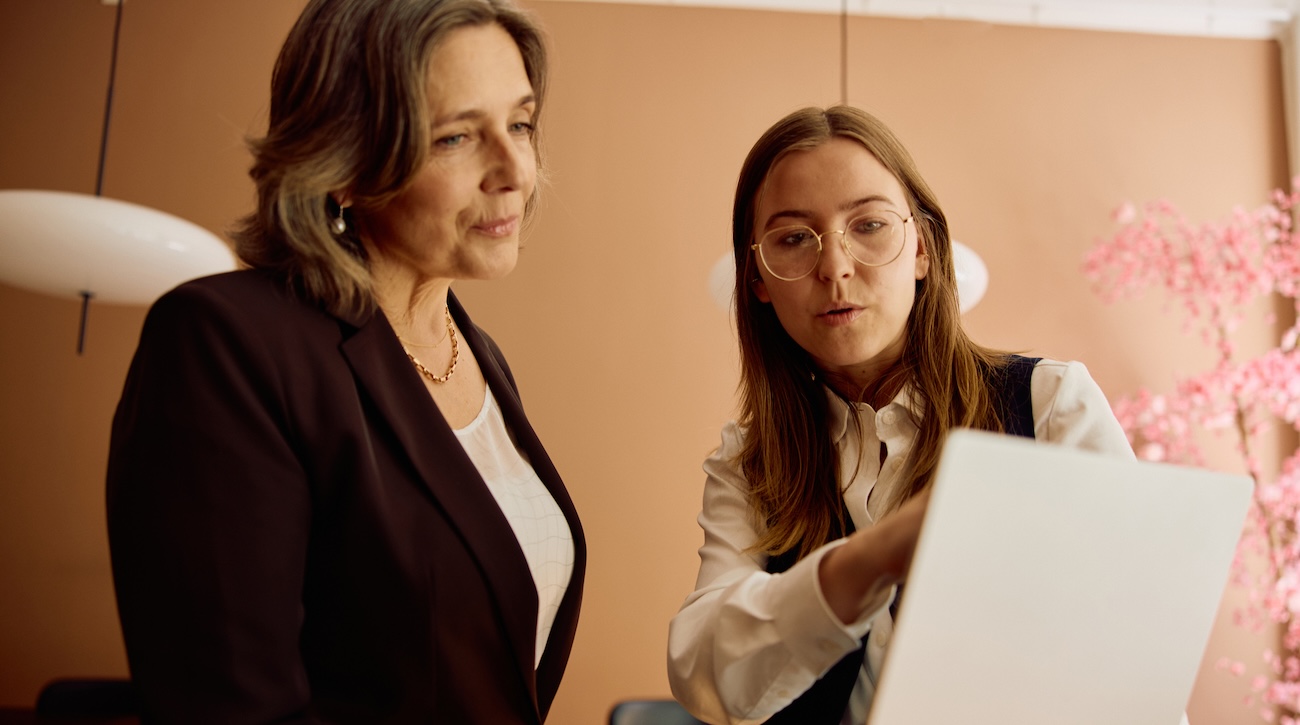 To kvinner i et møterom diskuterer arbeid ved en laptop på kontoret.