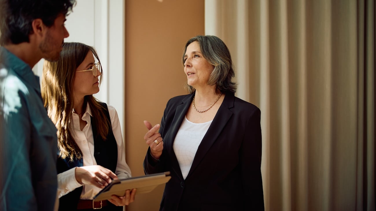 Sittende mann og kvinne pratende med datamaskin forran