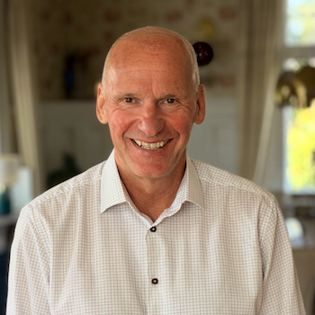 Mann i hvit skjorte som smiler bredt til kamera.