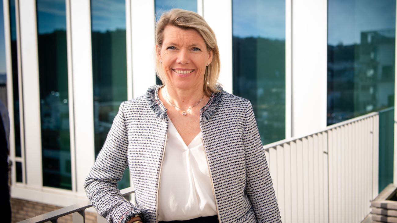 Kvinne som står på en takterrasse og smiler bredt til kamera.