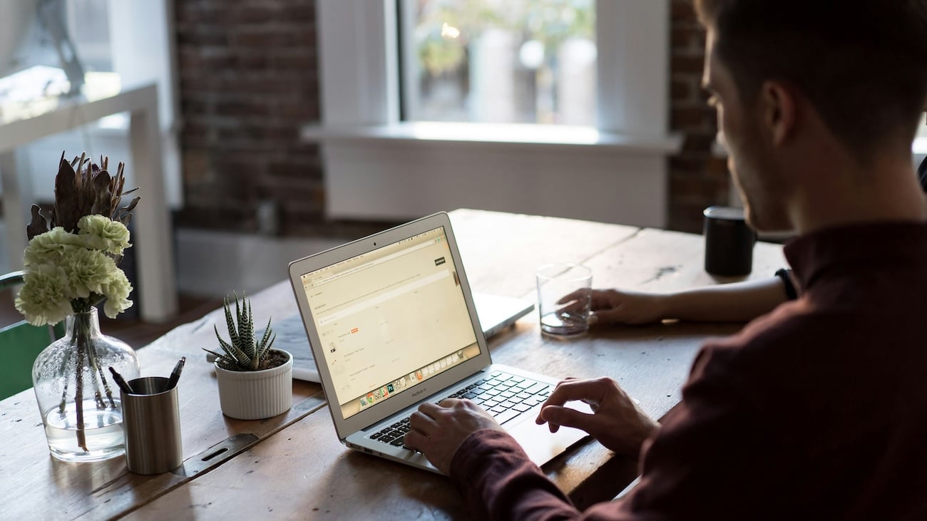 Mann søker jobb ved laptop i moderne hjemmekontor, med hjelp av kunstig intelligens (KI) – illustrasjon til artikkel om hvordan bruke KI i jobbsøknadsprosessen.