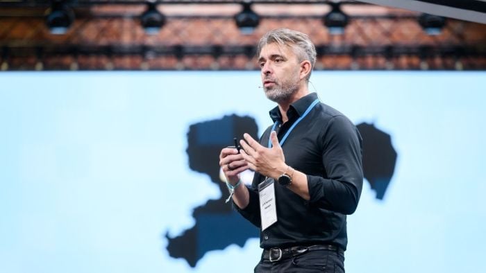 Formelt kledd mann som står på en scene og holder foredrag under Robotics festival i Dresden.