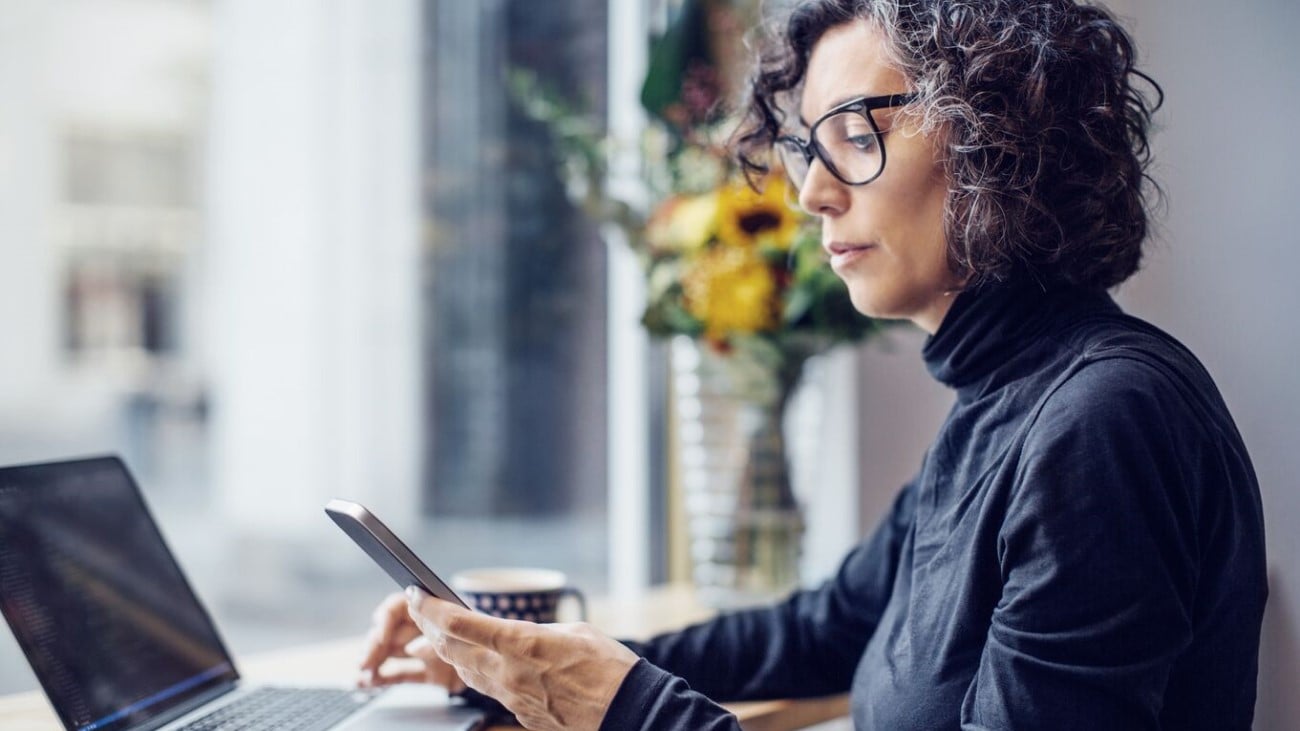 Kvinne som sitter og scroller på mobilen sin