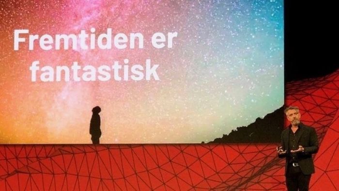 En mann som står på en scene og holder et foredrag. På skjermen bak han står teksten: "Fremtiden er fantastisk".