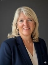 Portrettfoto av formelt kledd, lyshåret kvinne som smiler mot kamera.