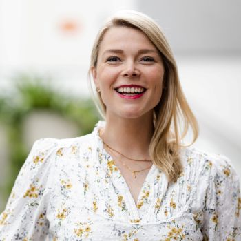 Kvinne i blomstrete bluse som smiler bredt til kamera.