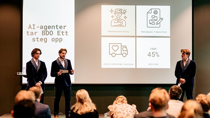 Tre unge gutter som står på en scenen og presenterer sitt case under NM i økonomi 2025.