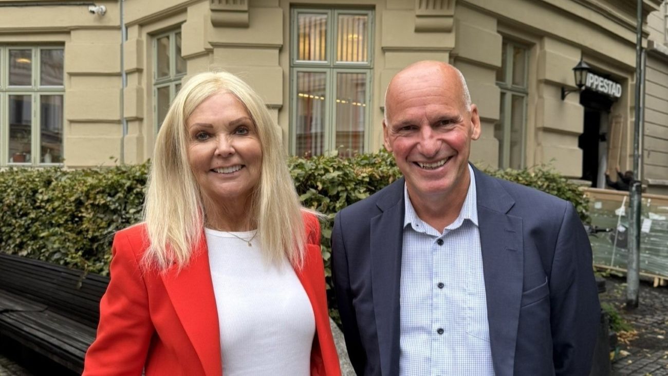 Mann og kvinne som står nære hverandre utendørs og smiler bredt til kamera. Begge formelt kledd.