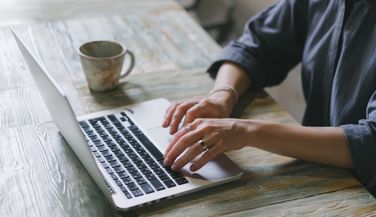 Person som skriver på laptop med kaffekopp på siden
