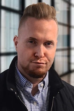 Nærbilde av mann som ser inn i kamera med et seriøst ansiktsuttrykk.