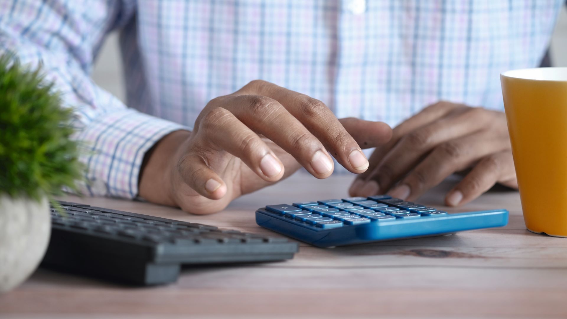 En mann som sitter ved et bord og taster på en kalkulator.