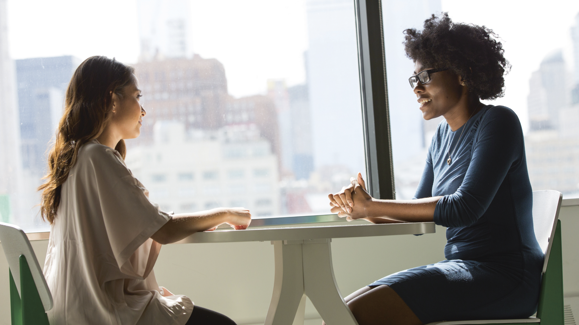 To kvinner som sitter ved et bord og fører en samtale om forhandlinger.