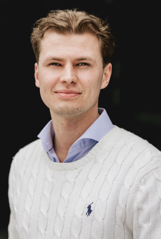 Portrettfoto av ung mann som smiler til kamera.