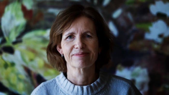 Kvinne som smiler forsiktig til kamera.