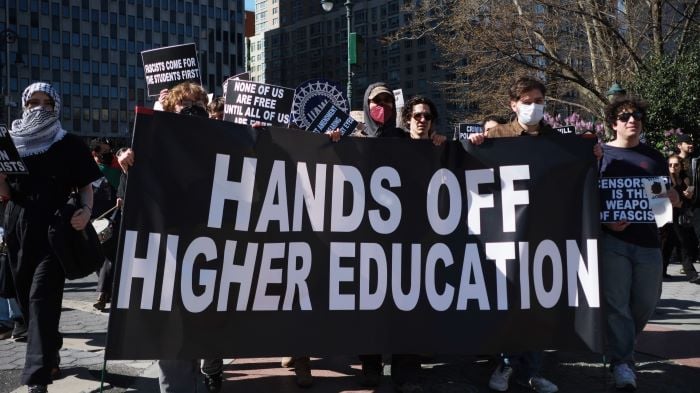 En demonstrasjon der demonstrantene holder et banner med teksten "Hands off higher education".