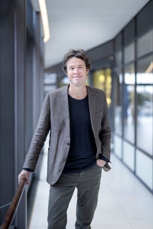 Formelt kledd mann som står i en gang mens han holder seg fast i et gelender. 