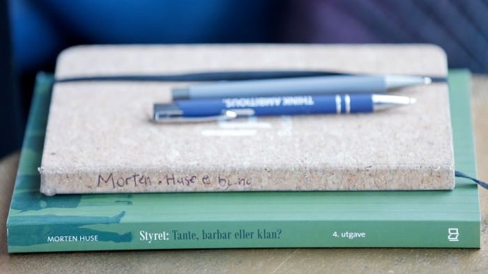 Nærbilde av bokbunke med penner liggende oppå.