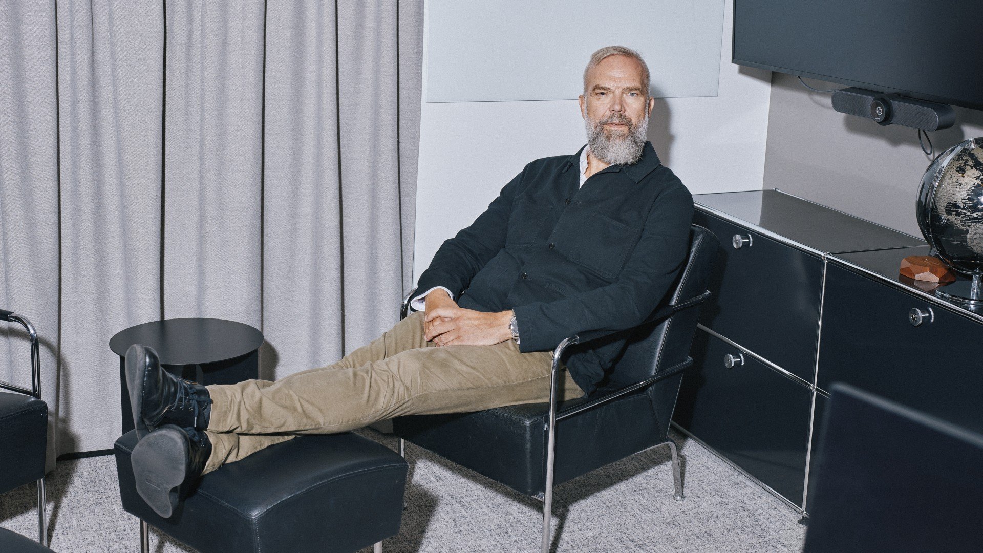 Mann som sitter lent bakover i en svart loungestol på et møterom og ser rett inn i kamera.