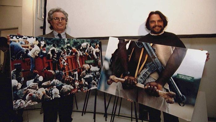 To menn som holder hvert sitt store fotografi og smiler bredt til kamera.