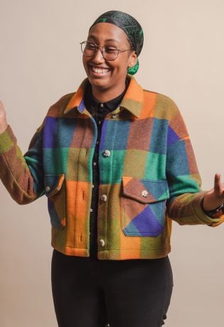 Ung kvinne som smiler bredt mens hun gestikulerer bredt med armene.