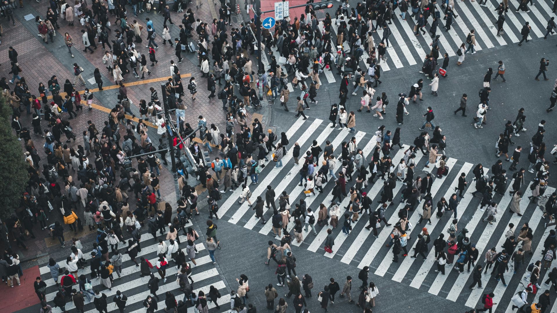 Et hektisk veikryss med stor folkemengde som går i alle retninger.