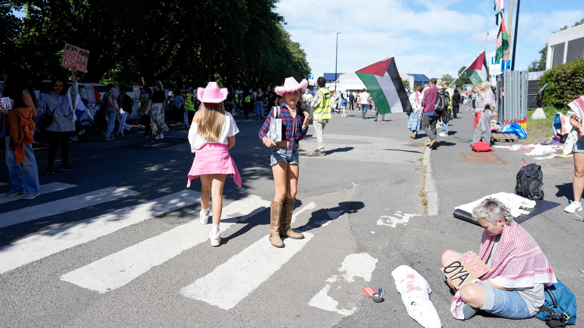 Mennesker som demonstrerer ved Øya-festivalen med skilt og palestinske flagg.