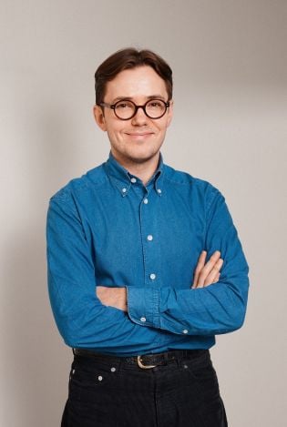 Portrettfoto av mann som står med armene i kryss mens han smiler til kamera.