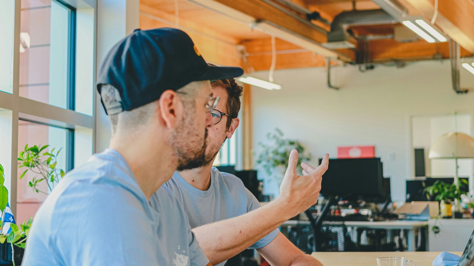 To mannlige kollegaer i samtale i et lyst og åpent kontorlandskap.