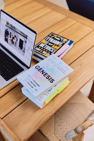 En PC på et trebord og forskningsbøker stablet rundt PC'en.